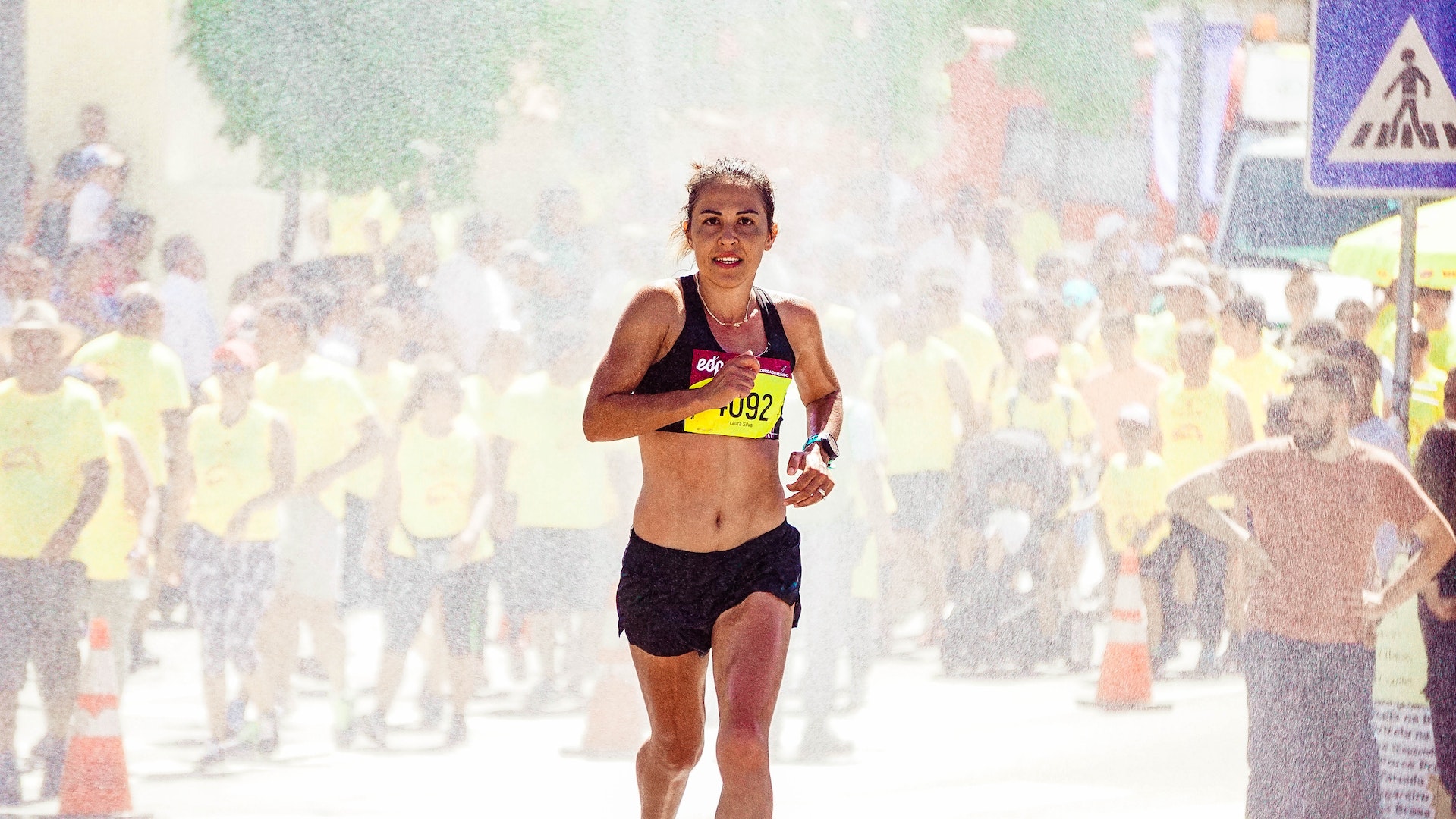 A female runner finishing race with crowd of people in the background.
